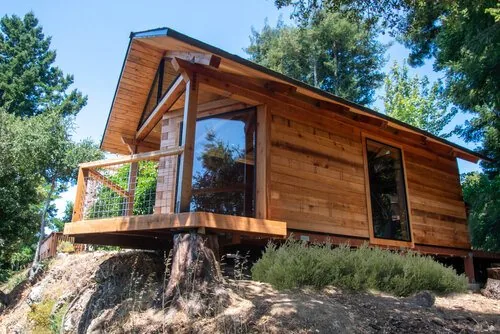 The finished Falcon's Nest prototype studio with deck in a redwood forest